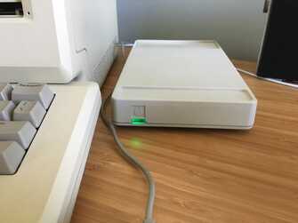 apple modem with green light illuminated on desk